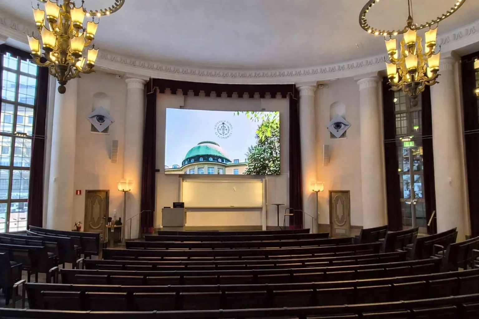 Handelshögskolans aula med LED-vägg mellan kolonnerna och klassiska ljuskronor
